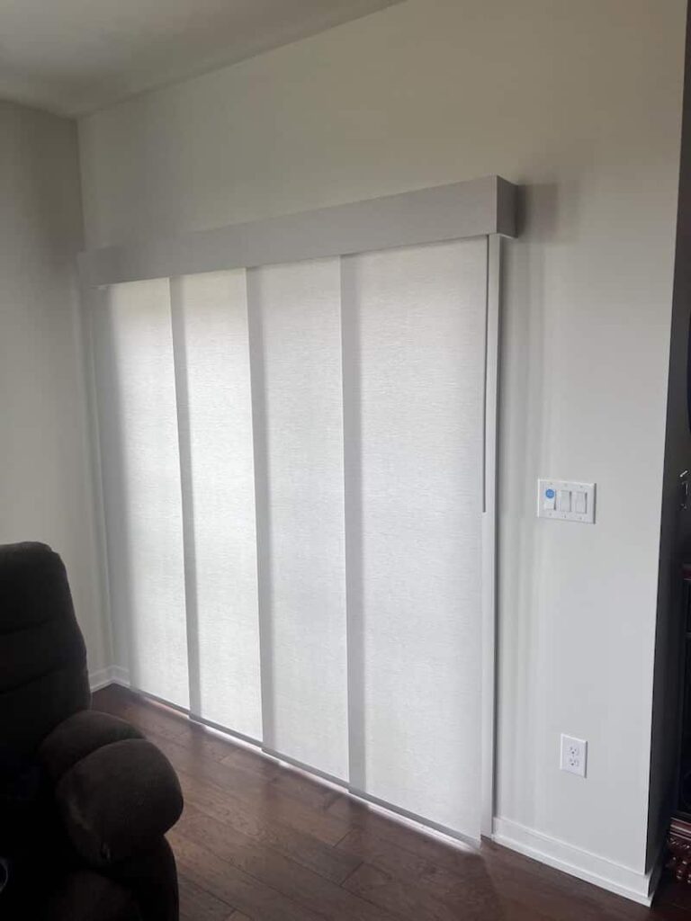 Vertical Blinds covering a double patio door in a living room near a sofa.