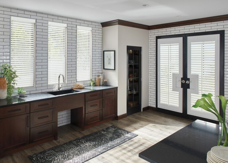 Three tall windows and two doors covered with composite shutters and surrounded by subway tile in a modern kitchen.