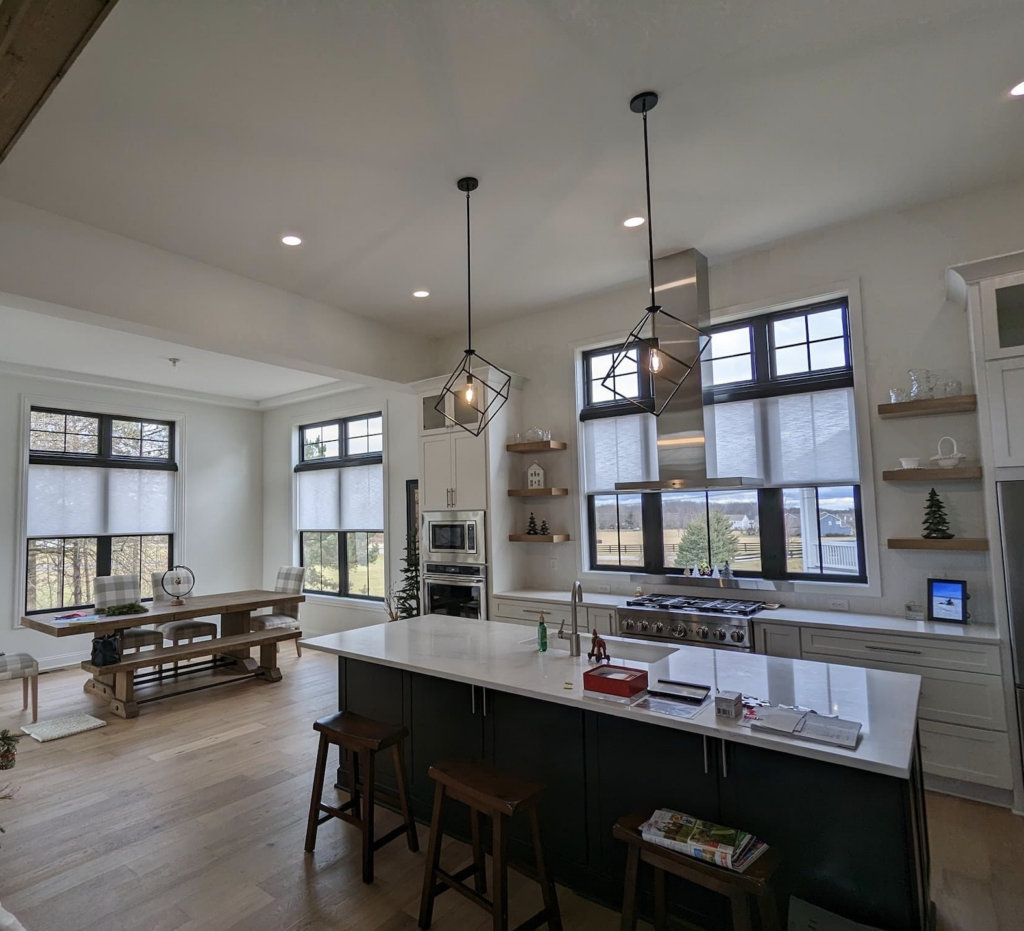 A kitchen and dining area with three large windows covered by Bartlett Blinds’ cellular shades, allowing ample natural light into the home.