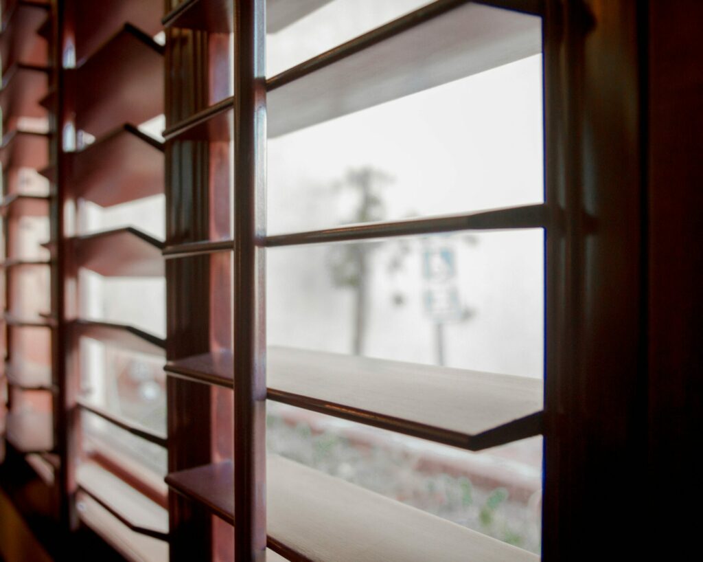 A basement window covered by Bartlett Blinds’ custom wood shutters, providing controlled light with timeless style and durability.